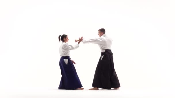 Man en vrouw in witte keikogi met aikido technieken, geïsoleerd op wit. Langzame beweging. — Stockvideo