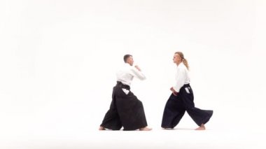 Kimonolu iki adam aikido teknikleri uyguluyor, beyazlar üzerinde izole edilmiş. Yavaş çekim.