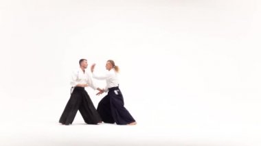 Kimonolu iki adam aikido teknikleri uyguluyor, beyazlar üzerinde izole edilmiş. Yavaş çekim.