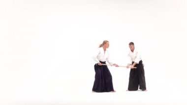 bokken kullanarak aikido yapan iki sporcu. İzole edilmiş, beyaz. Yavaş çekim.