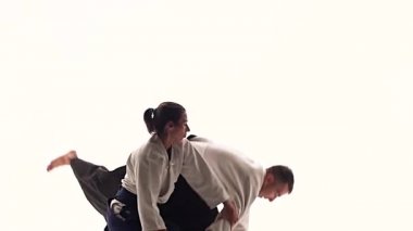 Beyaz keikogi giymiş erkek ve kadın aikido teknikleri gösteriyor, beyazdan izole edilmiş. Kapatın. Yavaş çekim.