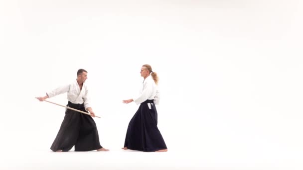 Två idrottare som utför aikido med bokken. Isolerad, vit. Långsamma rörelser. — Stockvideo