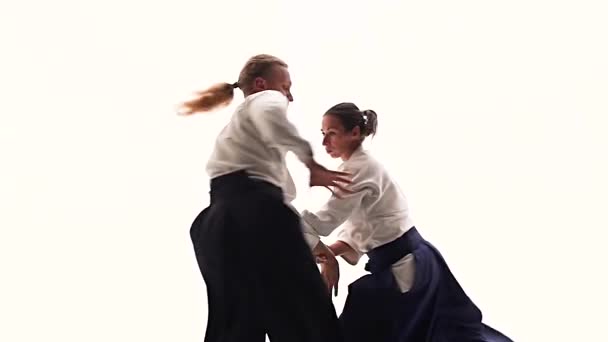 Homem e mulher em keikogi branco mostrando técnicas de aikido, isolado em branco. Fecha. Movimento lento . — Vídeo de Stock