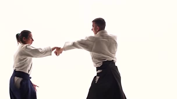 Hombre y mujer en keikogi blanco mostrando técnicas de aikido, aislados en blanco. De cerca. Movimiento lento . — Vídeo de stock