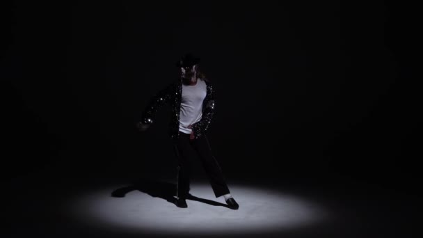 Joven y elegante hombre bailando con estilo Michael Jackson, centro de atención sobre un fondo negro . — Vídeo de stock