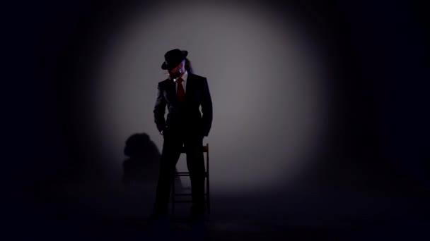 Elegant man in a black hat is dancing an erotic dance. Spotlight on a black background. — Stock Video