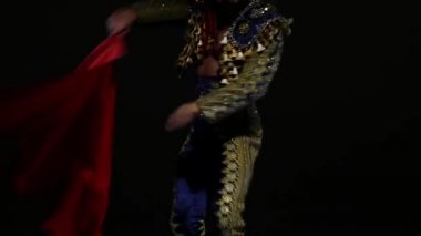 Mavi ve altın takım elbiseli Torero ya da tipik İspanyol boğa güreşçisi siyah arka plandaki spot ışıklarını izole etti. Yaklaşın, ağır çekim..