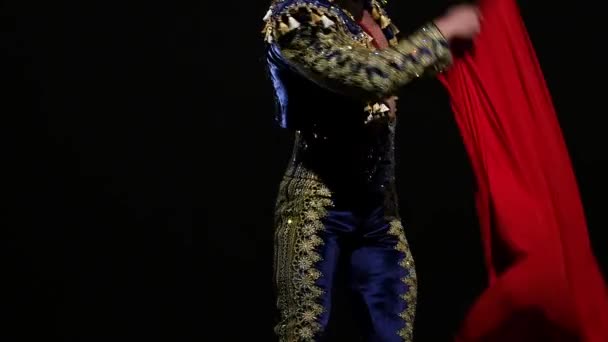 Torero im blau-goldenen Anzug oder typisch spanischer Stierkämpfer isoliert Scheinwerfer auf schwarzem Hintergrund. Nahaufnahme, Zeitlupe. — Stockvideo