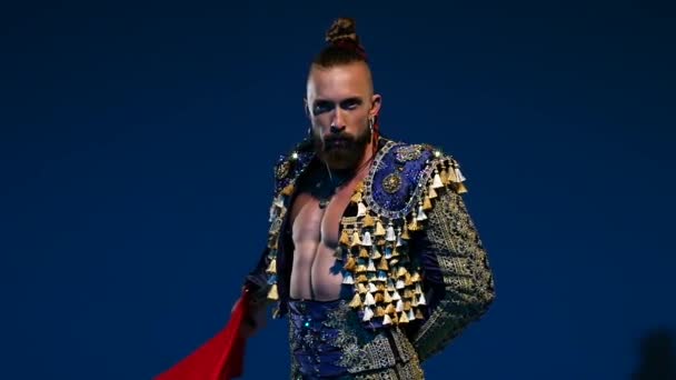 Torero in blue and gold suit or typical spanish bullfighter isolated spotlight on a blue background. Close up, slow motion. — Stock Video