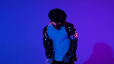 Michael Jackson tarzı dans eden genç şık bir adam, mavi arka planda spot ışıkları. Yaklaşın, ağır çekim..