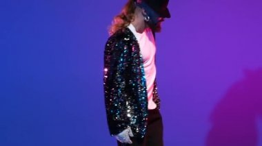 Michael Jackson tarzı dans eden genç şık bir adam, mavi arka planda spot ışıkları. Yaklaşın, ağır çekim..