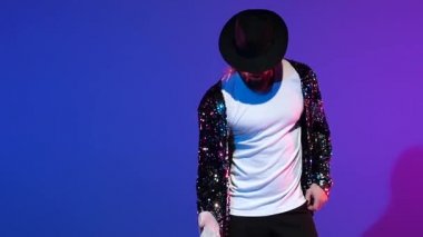 Michael Jackson tarzı dans eden genç şık bir adam, mavi arka planda spot ışıkları. Yaklaşın, ağır çekim..