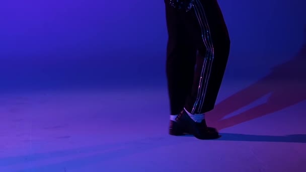 Young stylish man dancing in style Michael Jackson, spotlight on a blue background. Close up of legs, slow motion. — Stock Video