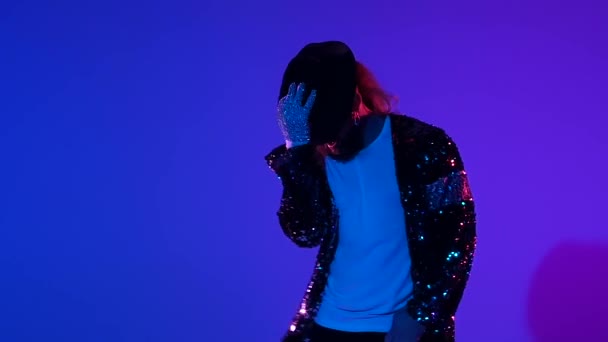 Young stylish man dancing in style Michael Jackson, spotlight on a blue background. Close up, slow motion. — Stock Video