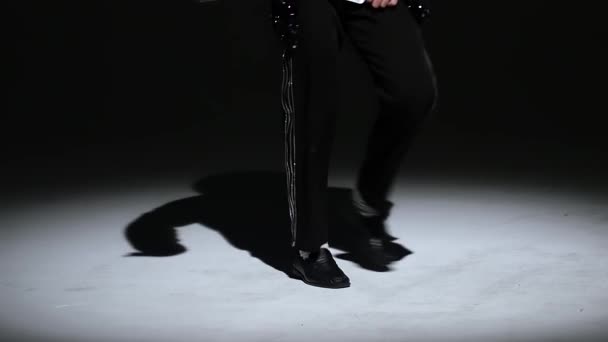 Young stylish man dancing in style Michael Jackson, spotlight on a black background. Close up of legs, slow motion. — Stock Video