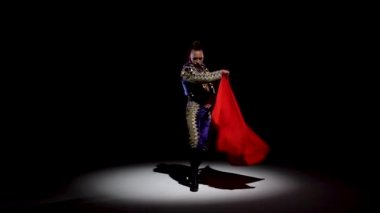 Mavi ve altın takım elbiseli Torero ya da tipik İspanyol boğa güreşçisi siyah arka plandaki spot ışıklarını izole etti. Yaklaşın, ağır çekim..
