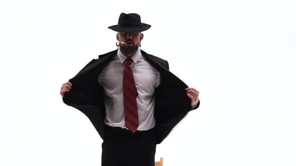 Elegancki mężczyzna w czarnym kapeluszu tańczy erotyczny taniec. Używa krzesła i papierosa. Białe tło. Zamknij się, zwolnij.. — Wideo stockowe