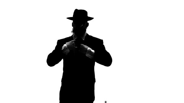 Σιλουέτα Κομψός άντρας με μαύρο καπέλο χορεύει έναν ερωτικό χορό. Χρησιμοποιεί μια καρέκλα και ένα τσιγάρο. Λευκό φόντο. Κλείσιμο, αργή κίνηση. — Αρχείο Βίντεο