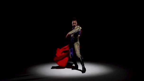 Torero in blue and gold suit or typical spanish bullfighter isolated spotlight on a black background. Close up, slow motion. — ストック動画