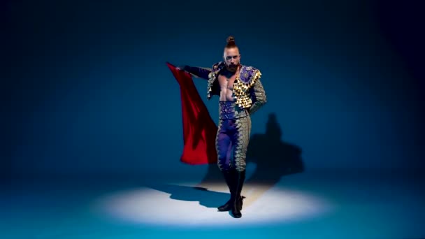 Torero in blue and gold suit or typical spanish bullfighter isolated spotlight on a blue background. Close up, slow motion. — Stock Video