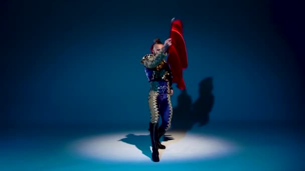 Torero im blau-goldenen Anzug oder typisch spanischer Stierkämpfer isoliert Scheinwerfer auf blauem Hintergrund. Nahaufnahme, Zeitlupe. — Stockvideo