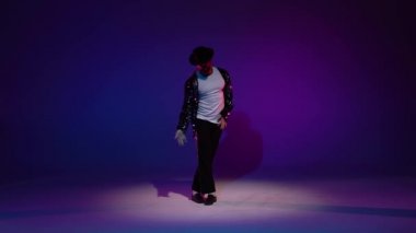 Michael Jackson tarzı dans eden genç şık bir adam, mavi arka planda spot ışıkları. Yaklaşın, ağır çekim..