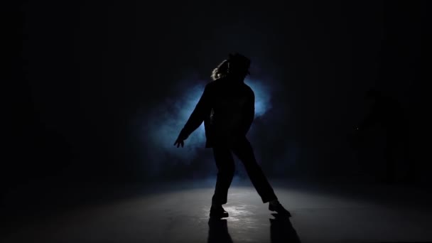 Egy fiatal férfi sziluettje, aki stílusosan táncol Michael Jacksonnal a füst kék hátterében. Bezárás, lassított felvétel.. — Stock videók