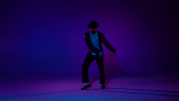 Young stylish man dancing in style Michael Jackson, spotlight on a blue background. Close up, slow motion. — Stock Video