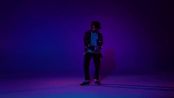 Young stylish man dancing in style Michael Jackson, spotlight on a blue background. Close up, slow motion. — Stock Video