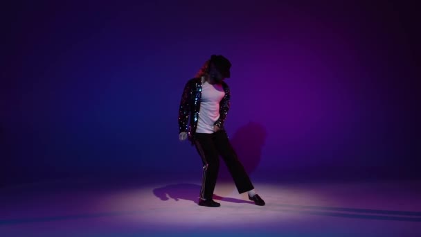 Joven hombre elegante bailando con estilo Michael Jackson, centro de atención sobre un fondo azul. Primer plano, cámara lenta . — Vídeo de stock
