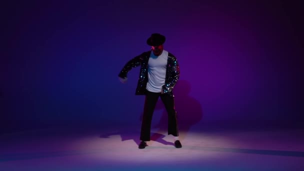 Młody, stylowy mężczyzna tańczący w stylu Michaela Jacksona, w świetle reflektorów na niebieskim tle. Zamknij się, zwolnij.. — Wideo stockowe