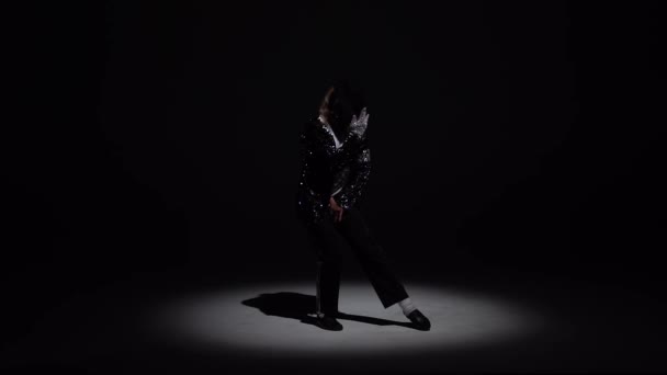 Young stylish man dancing in style Michael Jackson, spotlight on a black background. Close up, slow motion. — Stock Video