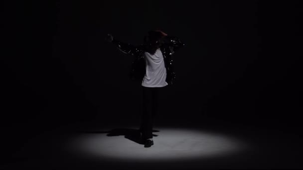 Young stylish man dancing in style Michael Jackson, spotlight on a black background. Close up, slow motion. — Stock Video