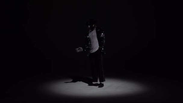 Молодий стильний чоловік танцює в стилі Майкла Джексона, прожектор на чорному тлі. Повільно, повільно.. — стокове відео