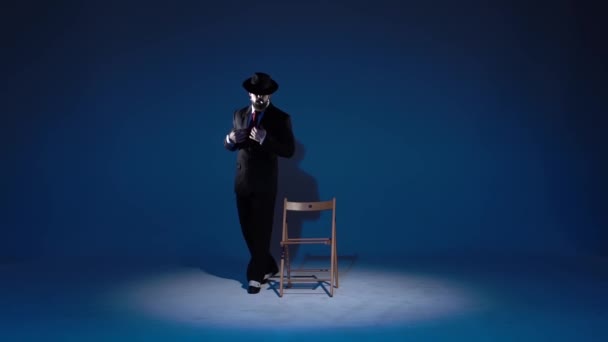 Elegant man in a black hat is dancing an erotic dance. Spotlight on a blue background. Close up, slow motion. — ストック動画