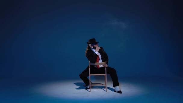 Elegant man i svart hatt dansar erotisk dans. spotlight på en blå bakgrund. Närbild, slow motion. — Stockvideo
