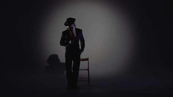 Elegant man in a black hat is dancing an erotic dance. Spotlight on a black background. Close up, slow motion. — 비디오