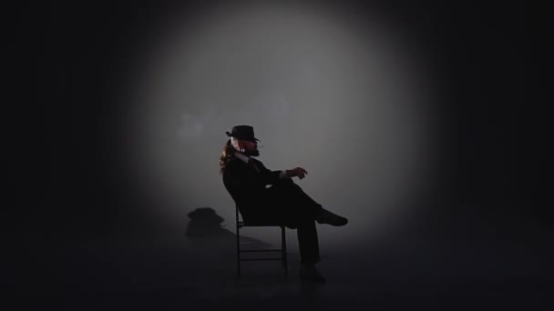 Un hombre elegante con un sombrero negro está bailando un baile erótico. Proyector sobre fondo negro. Primer plano, cámara lenta . — Vídeos de Stock
