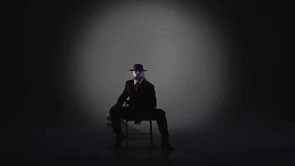 Eleganter Mann mit schwarzem Hut tanzt einen erotischen Tanz. Scheinwerfer auf schwarzem Hintergrund. Nahaufnahme, Zeitlupe. — Stockvideo