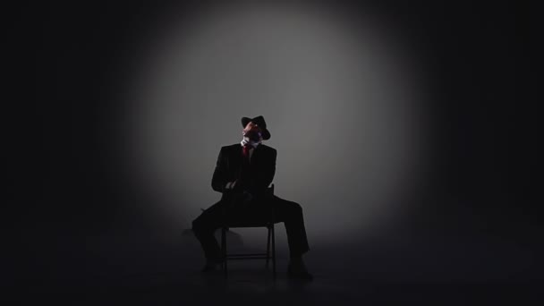 Un hombre elegante con un sombrero negro está bailando un baile erótico. Proyector sobre fondo negro. Primer plano, cámara lenta . — Vídeos de Stock