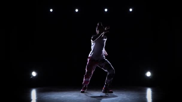 Nastolatek w luźnych ciuchach tańczy improwizując w czarnym studio. Król wymyśla ruchy. Umiejętności twórcze. — Wideo stockowe