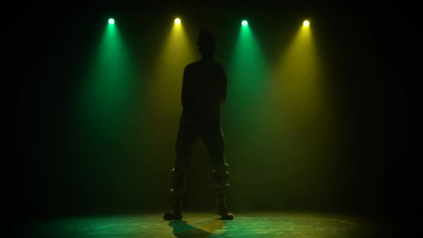 Man geniet van hiphop beweegt in donkere studio met rook. Groene en gele verlichting. Silhouet. — Stockvideo