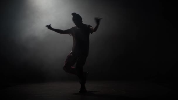 Silueta mladého muže tančícího svobodně v klubu, neonové světlo, spousta kouře. Módní oblečení. Silueta. — Stock video