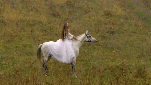 Két fehér menyasszonyi ruhás nő ül lovakon. — Stock videók