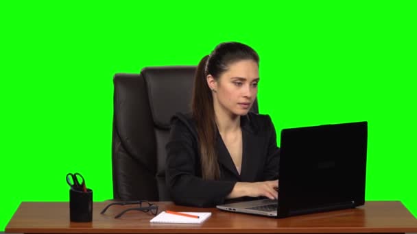 Η γυναίκα εργάζεται με ενθουσιασμό πίσω από ένα laptop, χαμογελά και απολαμβάνει το αποτέλεσμα. Πράσινη οθόνη. Αργή κίνηση — Αρχείο Βίντεο