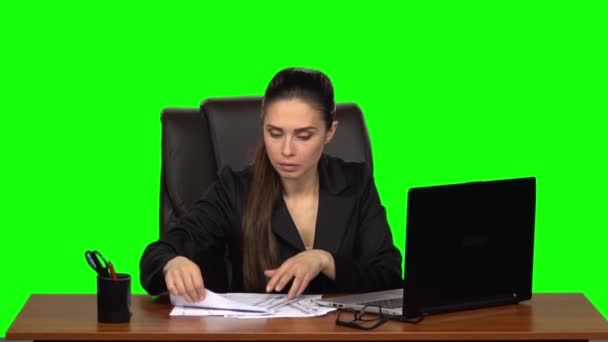 Mädchen, das am Laptop arbeitet, beginnt abrupt, Dokumente auf dem Tisch zu suchen und seufzt erleichtert, als sie sie findet. Green Screen. Zeitlupe — Stockvideo