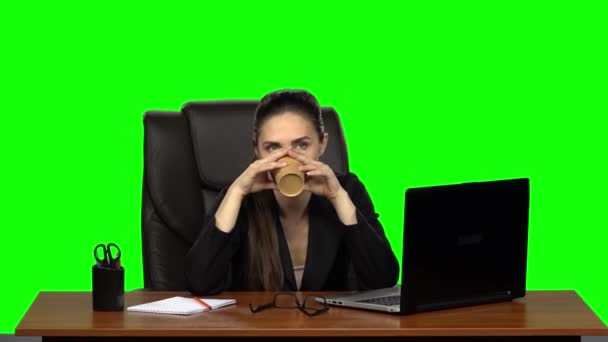 Business woman sitting at desk in leather chair and drink coffee. Green screen. Studio. Slow motion — ストック動画