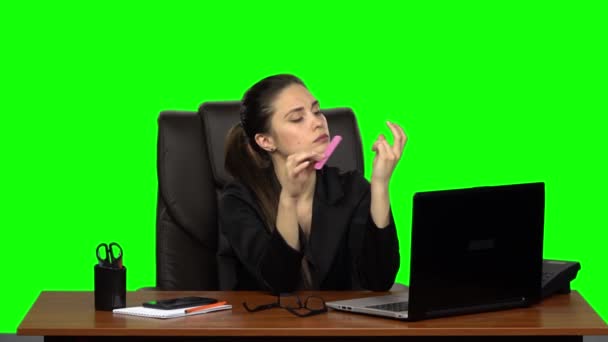 Girl at workplace is working on laptop, talking on phone and sawing nails. Green screen. Slow motion — ストック動画