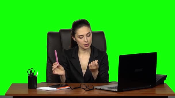 Girl at workplace is working on laptop, talking on phone and sawing nails. Green screen. Slow motion — ストック動画