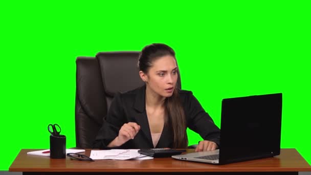 Бізнес-леді працює в ноутбуці, порівнює дані з рахунками на калькуляторі і робить записи в документах. Зелений екран. Повільний рух — стокове відео